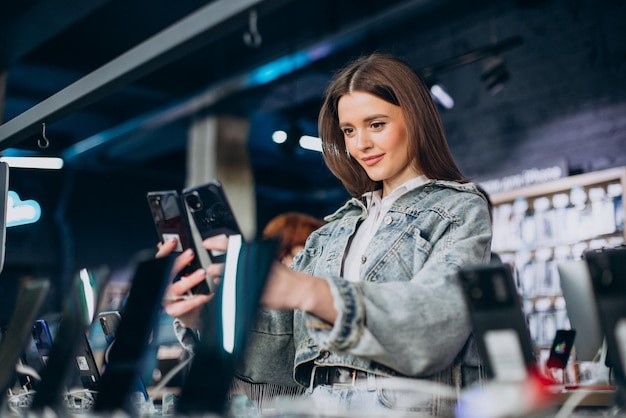 Woman choosing phone at technology store